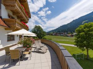 a patio with chairs and tables and an umbrella at Appartements Haflingerhof in Westendorf