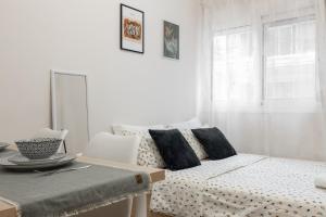 a white bedroom with a bed and a table and a window at Micro Studio 10 in Xanthi