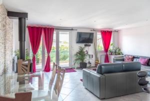 uma sala de estar com um sofá e cortinas vermelhas em Appartement Fuychaa Proche de Lyon , Eurexpo , stadium , Aréna em Meyzieu