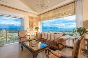 sala de estar con sofá, sillas y ventana grande en Luxe Villa Amfiario in Attica region, pool & breathtaking views! en Kálamos