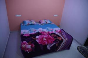 a bed with a blue comforter with flowers on it at Samyak bunglow in Dwarka