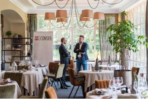 two people standing in a dining room with tables at Hotel de la Gaichel in Eischen