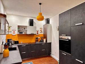 a kitchen with gray cabinets and a yellow wall at Grosse Wohnung in der Altstadt von Ettlingen in Ettlingen +14 photos