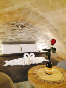 Zimmer mit einem Bett und einem Tisch mit einer Rose in einer Vase in der Unterkunft Domus Santi Medici Affittacamere in Massafra