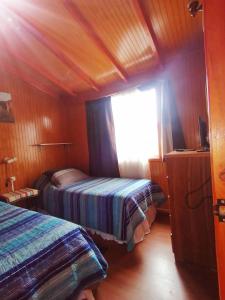 1 dormitorio con 2 camas en una cabaña de madera en Hospedaje Familiar Doña Juanita, en Puerto Montt