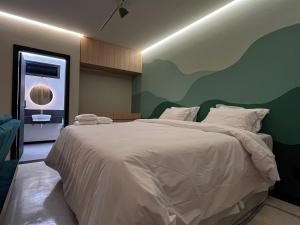 a bedroom with a white bed with a green wall at Theotokos Flats Apart-hotel in Piauí
