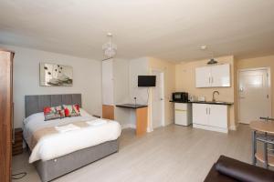a bedroom with a bed and a small kitchen at Saffron Studios in Orpington