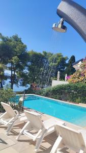 une piscine avec des chaises et une fontaine dans l'établissement Villa Penava, private beach, pool and 7min to Trogir, à Trogir