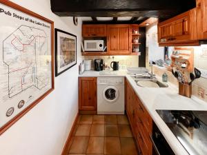 uma pequena cozinha com uma máquina de lavar roupa e um lavatório em Hidden Cottage em Spark Bridge