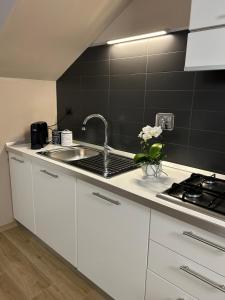 una cucina con armadi bianchi, lavandino e piastrelle nere di 12zero38 a Savigliano