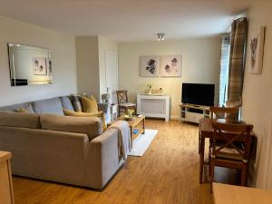a living room with a couch and a television at Conaglen, Glenloch View, Fort William 2-Bedroom Loch Side Flat in Fort William