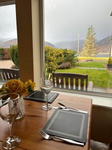 a table with glasses and a plate on it with a window at Conaglen, Glenloch View, Fort William 2-Bedroom Loch Side Flat in Fort William