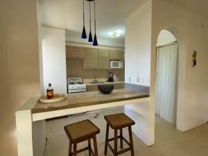 a kitchen with two bar stools and a counter at Cómodo apartamento Vacacional en Margarita 