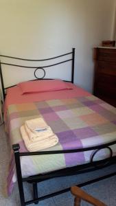 Una cama con un edredón a cuadros y toallas. en CASCINA NELLA CAMPAGNA ABRUZZESE, en Isola del Gran Sasso dʼItalia