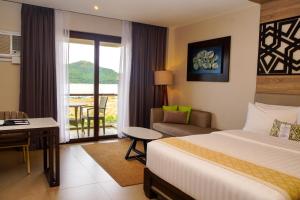 a hotel room with a bed and a desk and a balcony at Zuri Resort in Coron