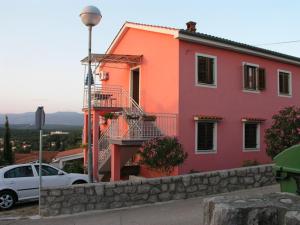 a pink house with a car parked in front of it at Apartmani Bura in Njivice