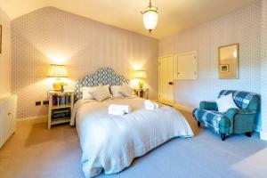 een slaapkamer met een groot bed en een blauwe stoel bij Pass the Keys Garden Cottage · Beautiful cottage nestled in 80 acres of parkland in Diddlebury