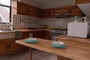 - une cuisine avec des placards en bois et une table en bois avec des bols dans l'établissement Estancia Mixtecas, à León