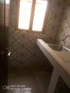 ein Bad mit einem Waschbecken und einem Fenster in der Unterkunft Raski immobilier in Ouagadougou