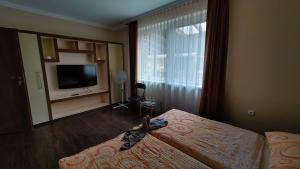 a bedroom with a bed and a tv and a window at Aquacentrum in Hajdúszoboszló