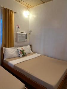 a small bedroom with a bed with a air conditioner at Cabin D at Bigang Munti in Batangas City