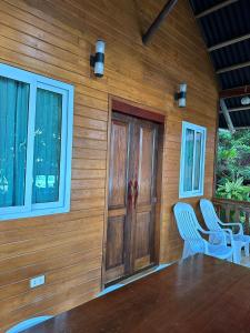 a wooden house with two chairs and a wooden door at Cabin D at Bigang Munti in Batangas City