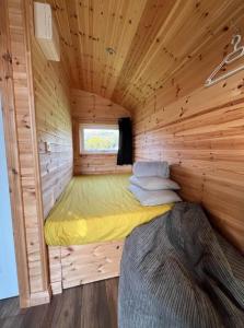 Bett in einer Holzhütte mit Fenster in der Unterkunft The Red Kite - 2 person Pet Friendly Glamping Cabin in Dungarvan