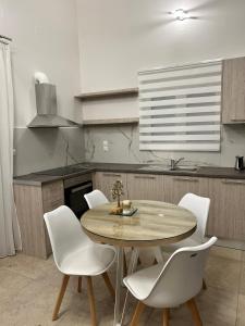 eine Küche mit einem Holztisch und weißen Stühlen in der Unterkunft TEGEA LUXURY SUITES Artemis in Tripolis