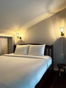 uma cama com lençóis brancos e almofadas num quarto em Stay Thought em Suratthani