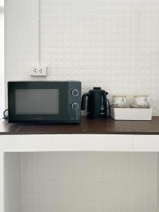 a microwave sitting on a counter with a coffee pot at Stay Thought in Surat Thani