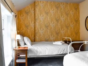 1 dormitorio con cama y pared amarilla en Beech Cottage en Carnforth