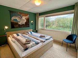 een slaapkamer met een bed met een stoel en een raam bij Beach House Wantveld Noordwijk aan Zee in Noordwijk aan Zee