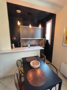 a kitchen with a black table with chairs and a counter at B Appartement in Malakoff
