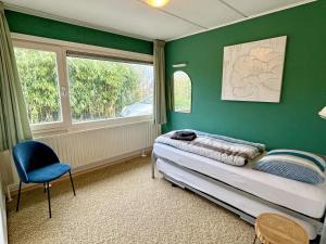 1 dormitorio con paredes verdes, 1 cama y 1 silla en Beach House Wantveld Noordwijk aan Zee en Noordwijk aan Zee