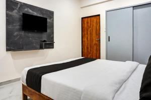 a bedroom with a bed and a flat screen tv at Super OYO Esta Inn in Pune
