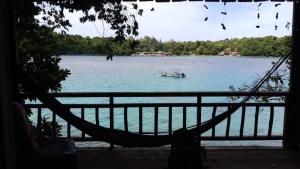 a hammock in front of a lake with a boat at Diara bungalow in Iboih