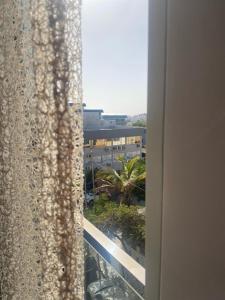 a window with a view of a building and a palm tree at SuAparts in Praia