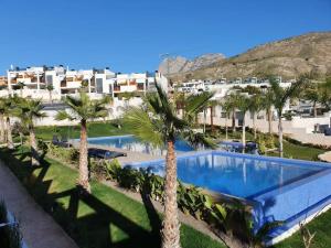 a resort with a swimming pool and palm trees at Villa Tropical - Alegría Village in Finestrat