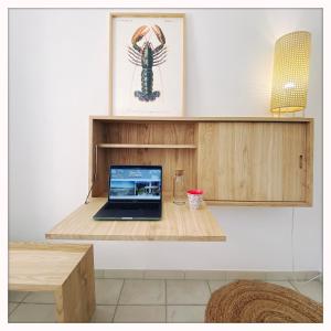 ラ・コティニエールにあるLes tranquilles d'Oléronの客室内の木製棚に座ったノートパソコン