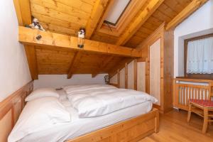a bed in a room with a wooden ceiling at mansarda Lungolago in Alleghe