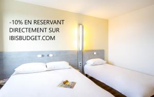 two beds in a room with a sign on the wall at Ibis Budget Fréjus St Raphaël plages in Fréjus