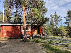 a small red house with a tree in front of it at Kivakko Saariselän paratiisi - Oma ranta & sauna in Saariselka