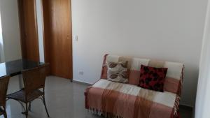 a room with a chair and a couch with pillows at Apartamento Central Curitiba in Curitiba