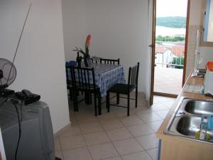 a kitchen with a table and chairs and a table and a sink at Apartmani Bura in Njivice