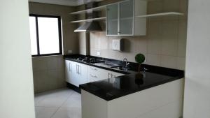 a kitchen with white cabinets and a black counter top at Apartamento Central Curitiba in Curitiba
