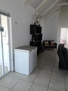 - un salon avec un réfrigérateur blanc et une table dans l'établissement The Tides Holiday Home, à St Helena Bay