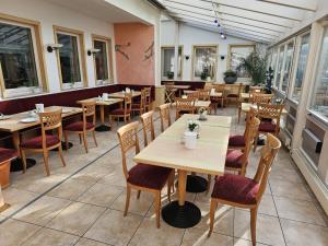 a restaurant with wooden tables and chairs and windows at Hotel Tennenloher Hof in Erlangen