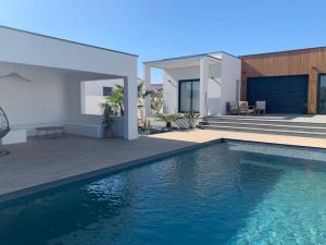une maison avec une piscine en face d'une maison dans l'établissement Villa contemporaine avec piscine et grand jardin, à Bernis