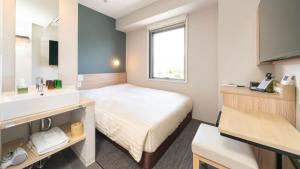 um quarto de hotel com uma cama e um lavatório em Super Hotel Fujikawaguchiko Tennenonsen em Fujikawaguchiko