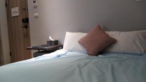 a bed with two pillows and a table with a night stand at 蘆思特六合民宿 in Kaohsiung